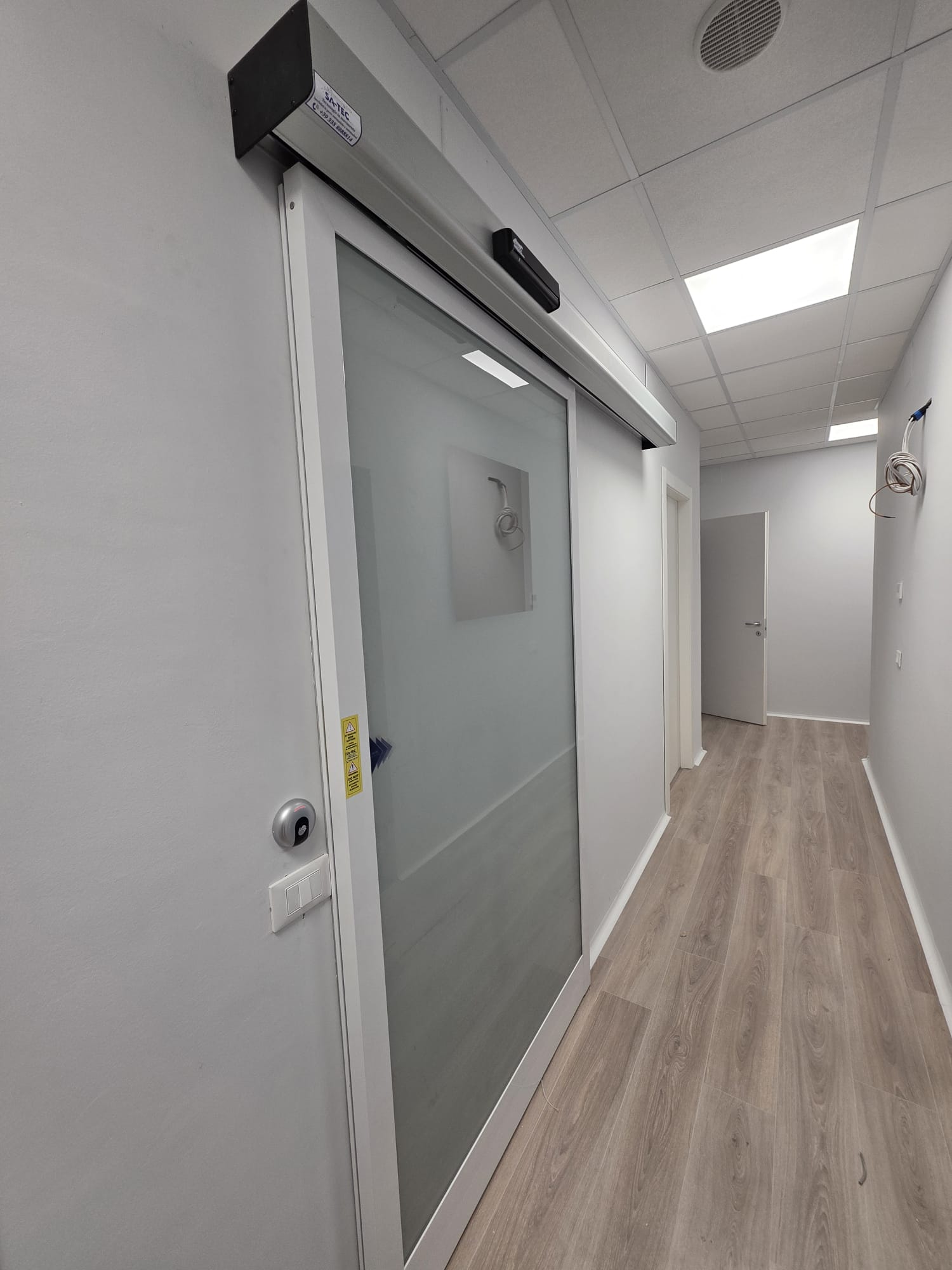 Porta scorrevole automatica SA-TEC con vetro satinato in corridoio